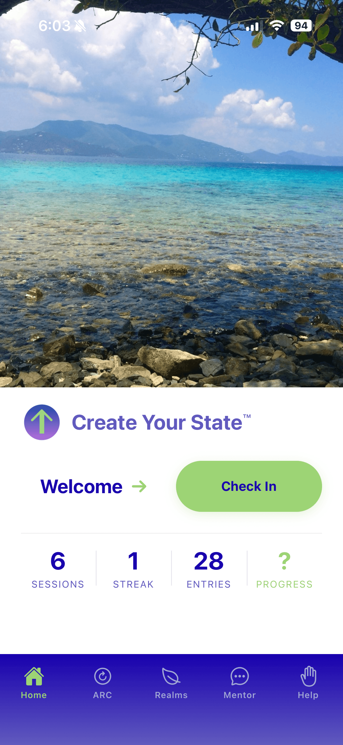 The Create Your State™ app home screen on an iPhone: a photograph of a clear turquoise shoreline with hills beyond it, above the app logo, a Welcome greeting beside a green Check In button, a row reading 6 sessions, 1 streak, 28 entries and progress, and a bottom navigation bar with Home, ARC, Realms, Mentor and Help.
