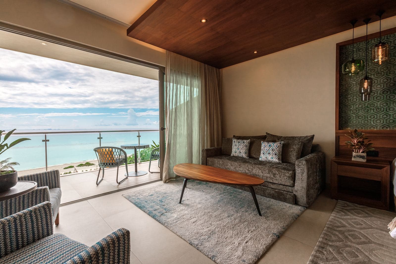 King Suite Ocean View: a sofa, coffee table and armchairs beside open balcony doors, with the turquoise sea beyond