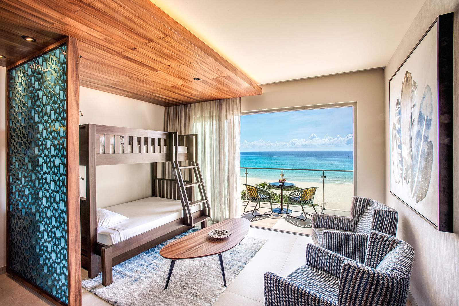 Family King Suite Ocean View: a bunk bed and sitting area facing a balcony with a view of the beach and sea
