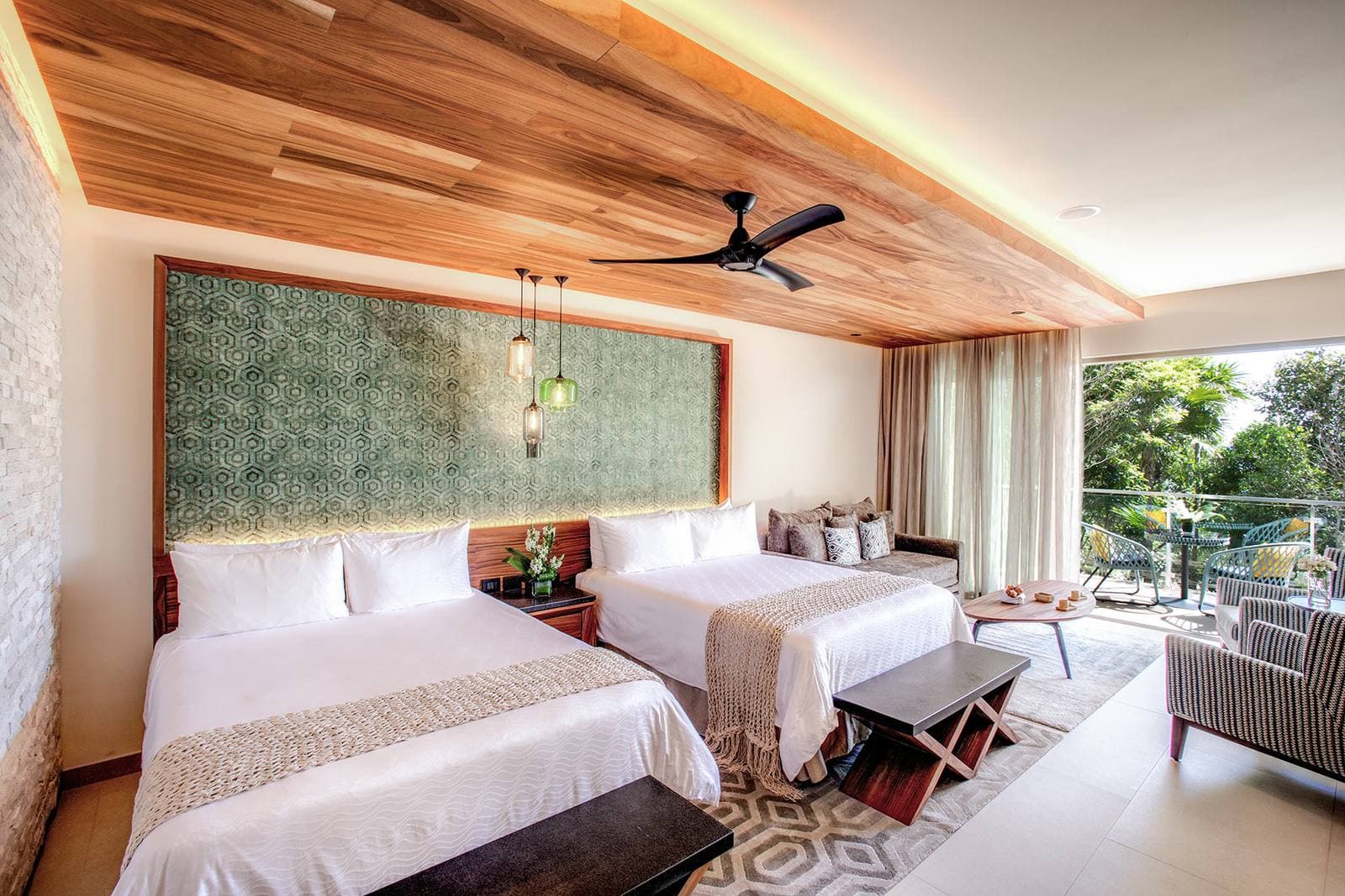 Queen Suite: two queen beds under a wood ceiling, a sofa and armchairs, and a balcony looking onto the jungle